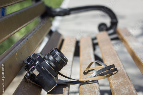 Old film photo camera on a bench in a park