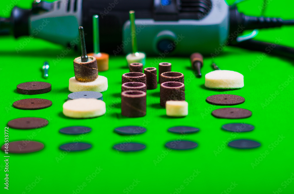 A gray drill behind of the drilling accessories on green background A gray drill behind of the drilling accessories on green background