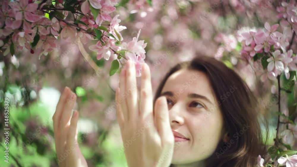Beautiful woman sniffing flowers in the spring garden Beautiful woman sniffing flowers in the spring garden
