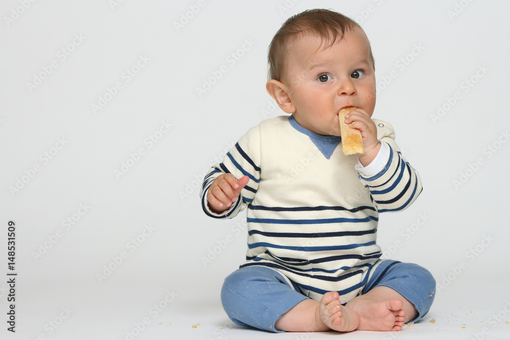 Seated baby crunches a biscuit Seated baby crunches a biscuit