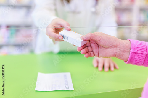 Senior customer in pharmacy buying and taking a box of medication Close up