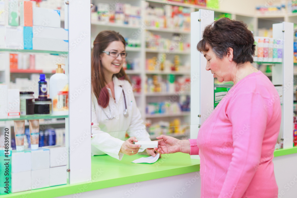 Pharmacist giving medication to a senior customer at pharmacy