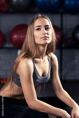 Portrait of beautiful caucasian fitness woman resting in gym after workout. Warm color toned image