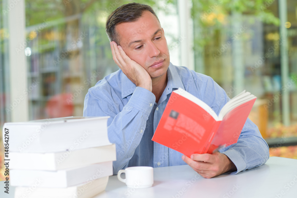 Man reading book, looking bored Man reading book, looking bored