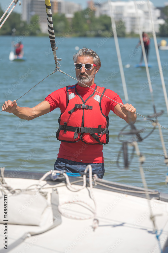 Naklejka premium portrait of mature sportsman near catamaran