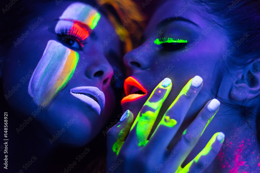 Sexy lesbian fashion models kissing in uv neon light with fluorescent  glowing Body Art make-up . Low key dark image. Soft focus image. foto de  Stock | Adobe Stock