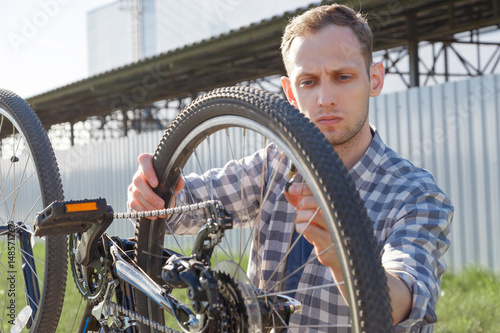 A concentrated craftsman is diagnosing bike malfunctions on the street.