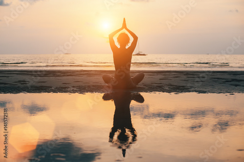 Yoga woman silhouette on the beach  bright sunset.