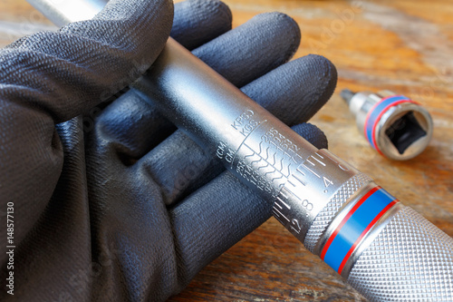 Mechanic's hand in the working glove holds the torque wrench photo