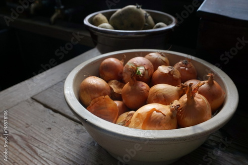 Organic brown skin onions in a ceramic bowl in natural light, in a traditional kitchen