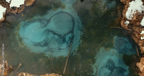 The magic miracle of nature is a geyser lake. Amazing view from above on a geyser lake of azure color. Unfreezing thermal spring - a geyser lake fancifully changes the pattern on the water surface. photo