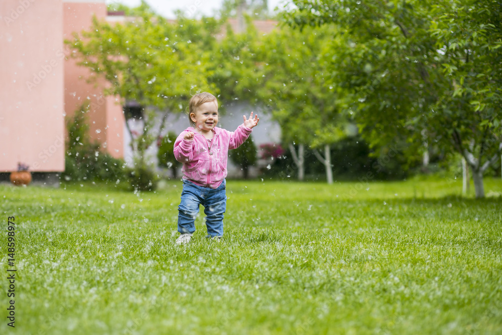 Litlle baby girl playing with poplar fluff on the green park outdoor. Litlle baby girl playing with poplar fluff on the green park outdoor.
