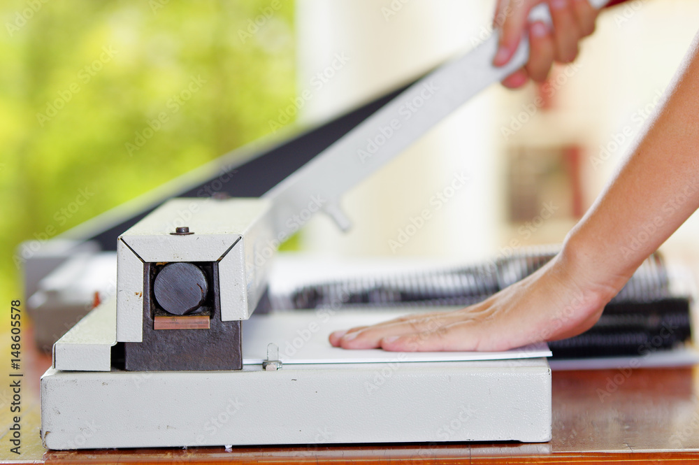 Man using manual paper cutter to cut the bills printed in the sheets of paper, on a wooden table, Manufacture work Man using manual paper cutter to cut the bills printed in the sheets of paper, on a wooden table, Manufacture work