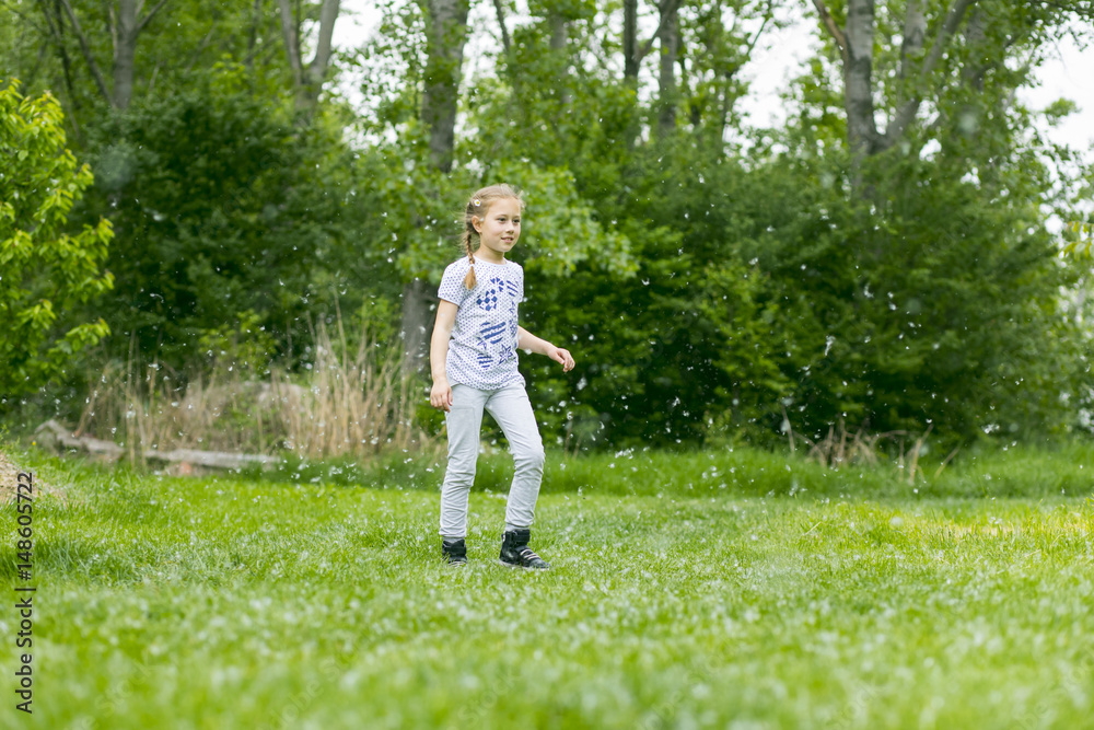 Little girl  playing with poplar fluff on the green park outdoor.