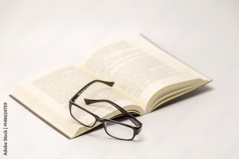 Open thick book with glasses on it isolated on white background Open thick book with glasses on it isolated on white background