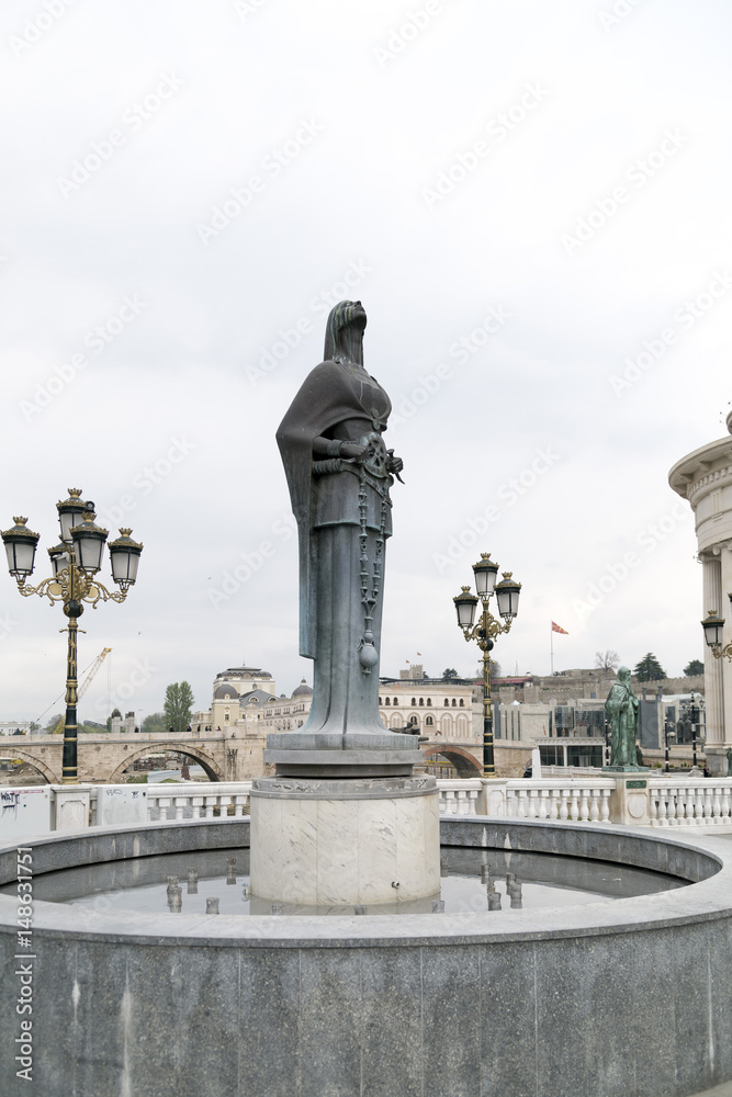 Bronze sculpture of a stylized female figure holding a rosary symbol in Skopje
