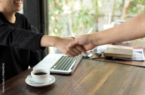 Success concept hand shaking agreement deal with cup of coffee and laptop