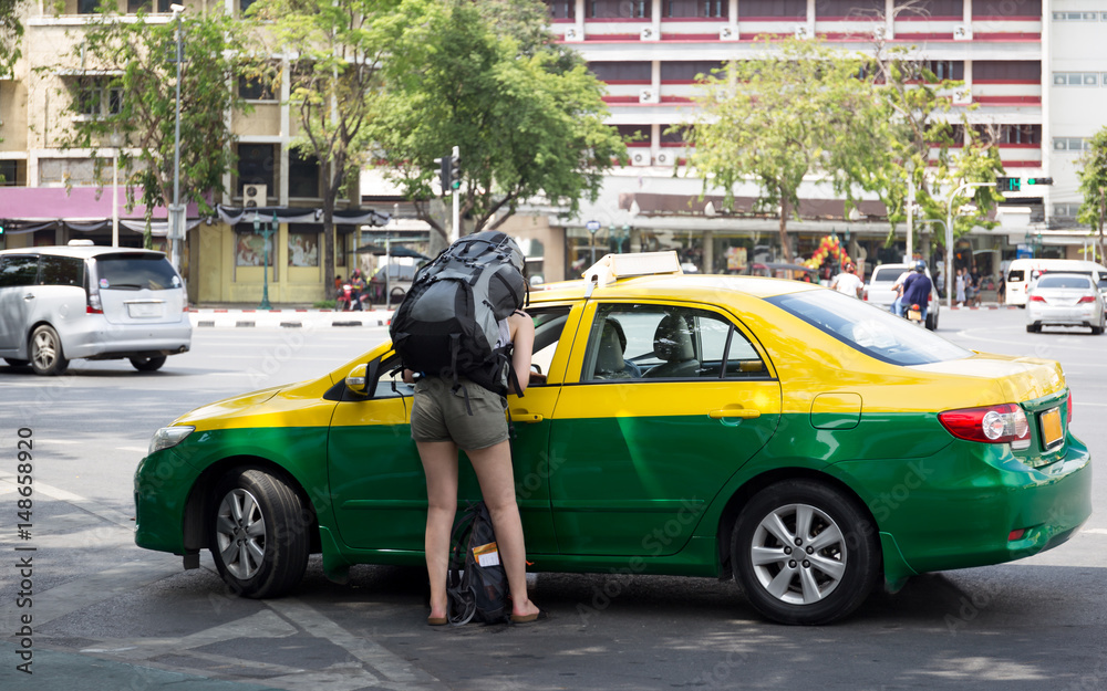 Fototapeta premium Tourist woman with backpack talking to taxi driver