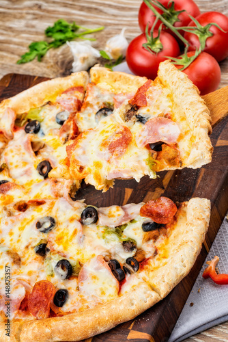 Photo of a hot pizza on wooden background.