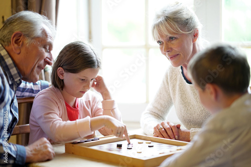 Grand-parents with grandkids playing checkers