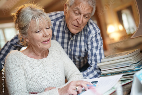 Senior couple sitting at desk looking at photo album