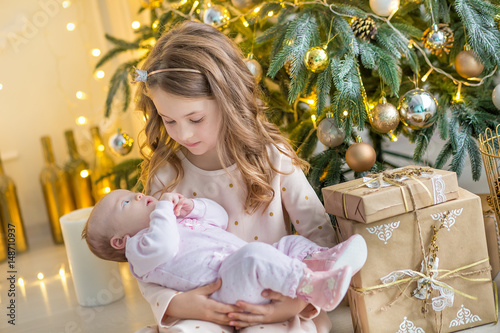 Family on Christmas eve at fireplace. Kids opening Xmas presents. Children under Christmas tree with gift boxes. Decorated living room with traditional fire place. Cozy warm winter evening at home.