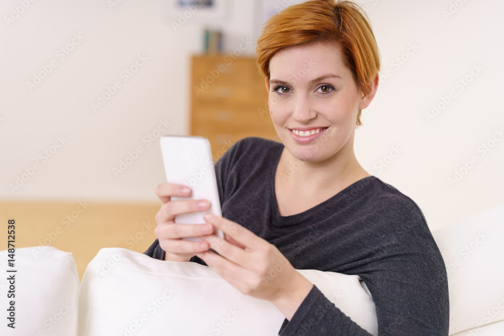 junge frau mit mobiltelefon auf dem sofa zu hause junge frau mit mobiltelefon auf dem sofa zu hause
