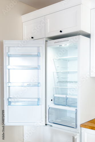 Opened new empty fridge with shelves and drawers for meat and vegetables. 