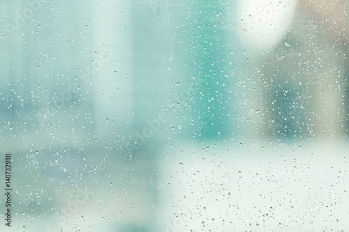 Rain dropping at a window or high building with a city view outside,city life concept.