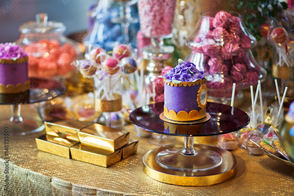 Violet cake with golden icing stands on the glass plate