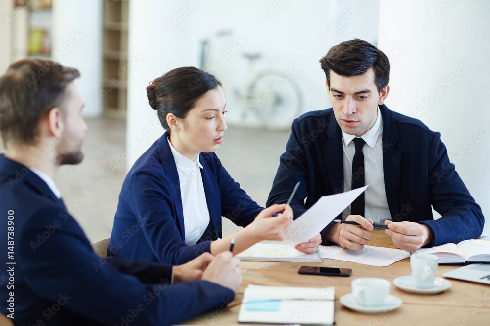 Group of business co-workers discussing paper held by woman Group of business co-workers discussing paper held by woman