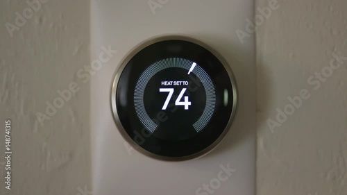 Man Increasing Temperature of Smart Thermostat Gadget At Home