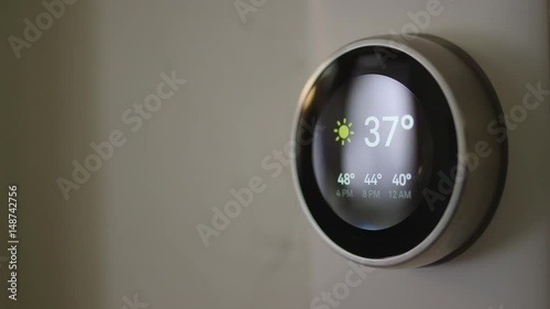 Woman Adjusting Smart Thermostat Gadget At Home
