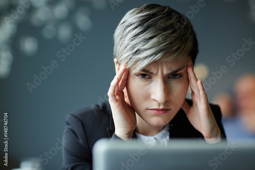 Frowning businesswoman with headache looking at camera
