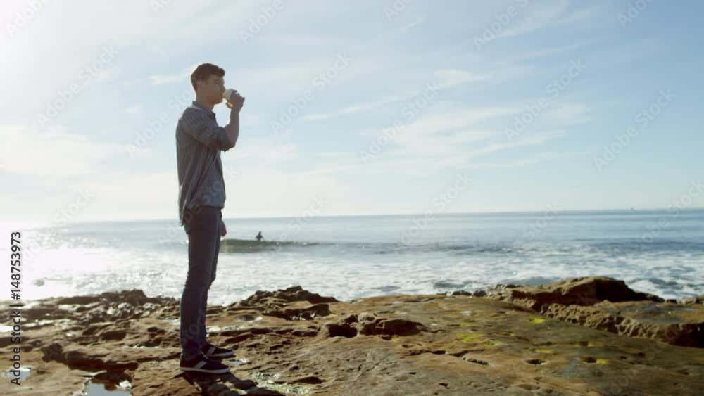 Joyful young man is drinking coffee on a seashore Joyful young man is drinking coffee on a seashore