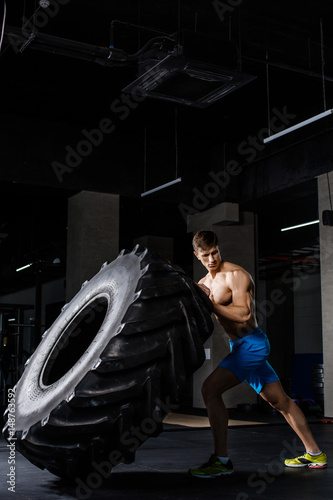 Crossfit training - man flipping tire in gym