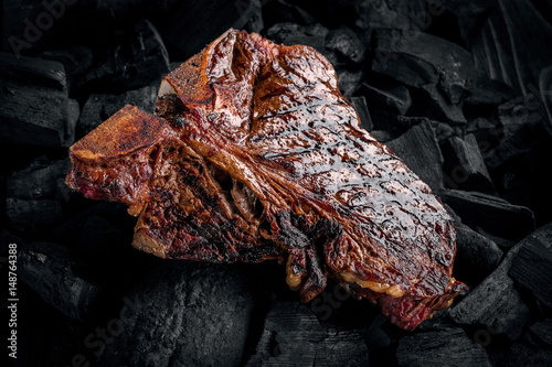 Grilling a tasty tender marinated t-bone steak on a coals. photo