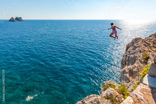 A boy is jumping from the cliff. Holidays in Montenegro
