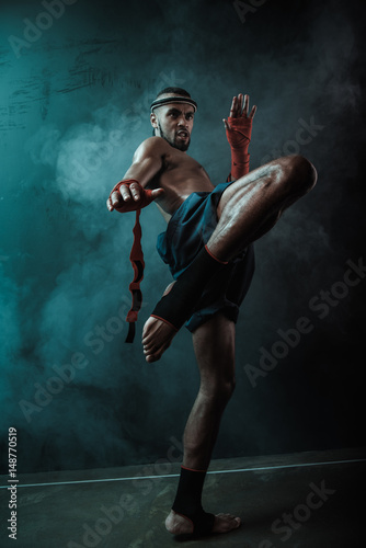 Low angle view of determined Muay Thai fighter training Thai boxing, ultimate fight concept