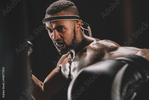 portrait of angry muay thai fighter training isolated on black photo