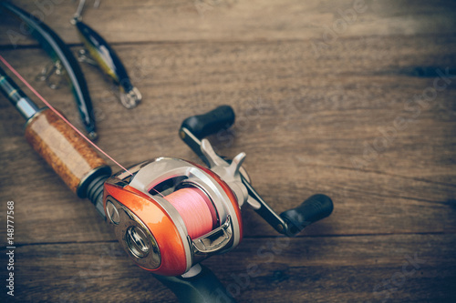 Fishing tackle - Baitcasting Reel, hooks and lures on  wooden background photo