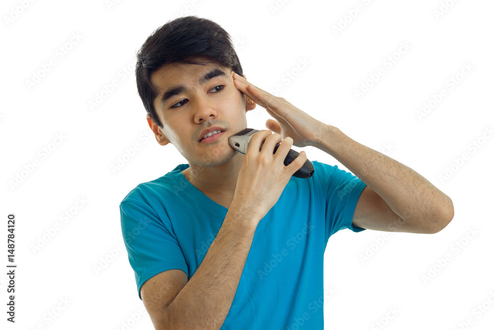 a young guy in the blue shirt shaves his face and looks toward a young guy in the blue shirt shaves his face and looks toward
