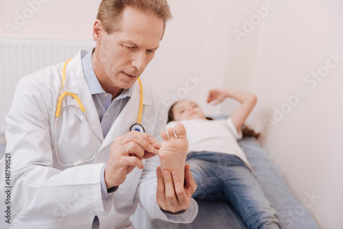 Obraz na plátně Clever precise specialist carefully studying patients feet