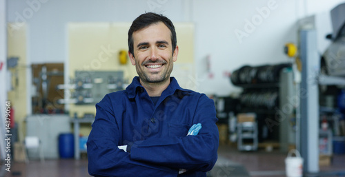 Portrait of a young beautiful car mechanic in a car workshop, in the background of a car service Concept repair of machines, fault diagnosis, repair specialist, technical maintenance on-board computer photo