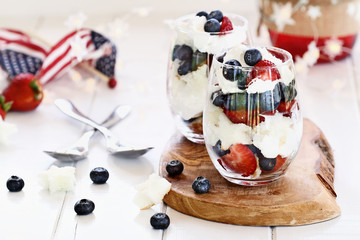 Trifle made with blueberries, strawberries, whipped cream and star shaped pound cake sitting on a Fourth of July picnic table. Shallow depth of field with selective focus.