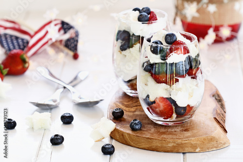 Картината върху платно Trifle made with blueberries, strawberries, whipped cream and star shaped pound cake sitting on a Fourth of July picnic table
