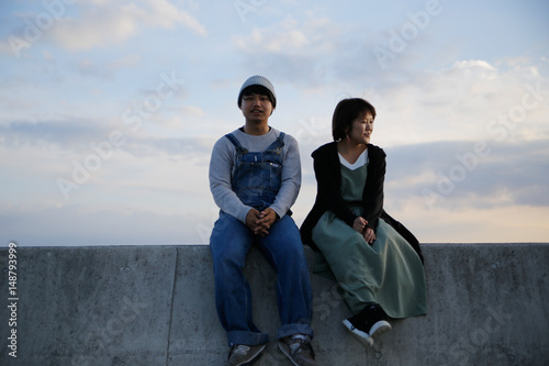 young couple sitting in a breakwater © lansa