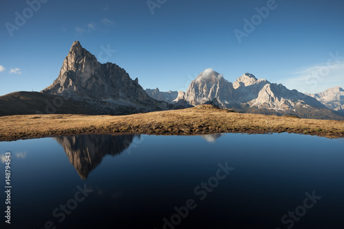 Ra Gusela reflects itself over a little alpine lake in Dolomites at evening