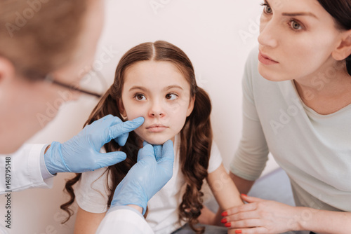 Focused prominent dermatologist examining little ladies skin