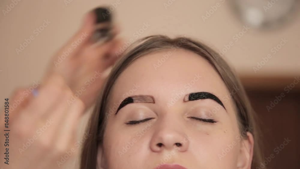 Professional make-up artist drawing eyebrows of client with henna